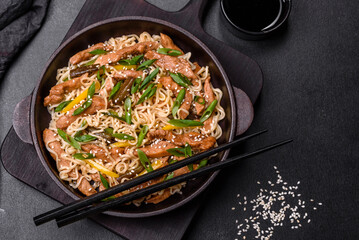 Tasty dish of Asian cuisine with rice noodles, chicken, asparagus, pepper, sesame seeds and soy sauce