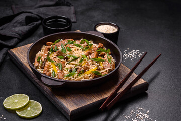 Tasty dish of Asian cuisine with rice noodles, chicken, asparagus, pepper, sesame seeds and soy sauce
