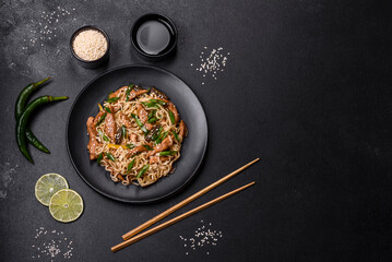 Tasty dish of Asian cuisine with rice noodles, chicken, asparagus, pepper, sesame seeds and soy sauce