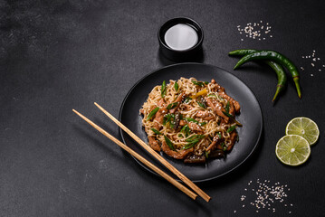 Tasty dish of Asian cuisine with rice noodles, chicken, asparagus, pepper, sesame seeds and soy sauce