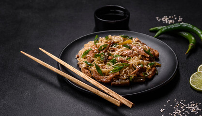 Tasty dish of Asian cuisine with rice noodles, chicken, asparagus, pepper, sesame seeds and soy sauce