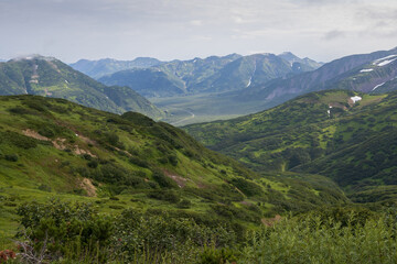 Fototapeta na wymiar Summer mountain landscape. View from the mountains to the valley. Travel, tourism and hiking on the Kamchatka Peninsula. Beautiful nature of Siberia and the Russian Far East. Kamchatka Krai, Russia.