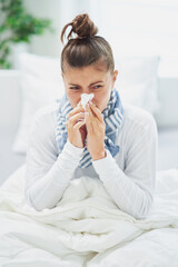 Young brunet woman sick in the bed with tissue