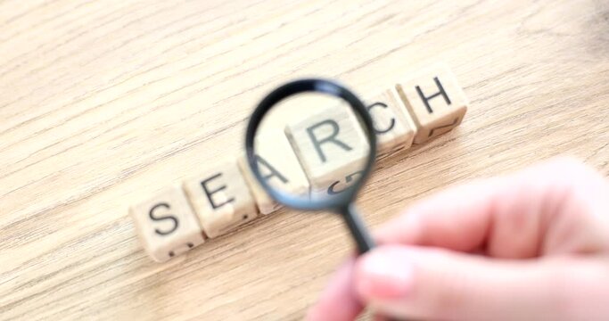 Magnifying glass and search word written on cube on wooden background