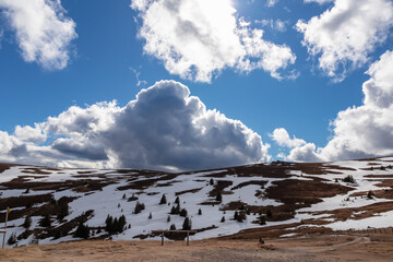 Scenic view on summit cross of mountain peak Zingerle Kreuz seen from Wolfsbergerhuette, Saualpe, Carinthia, Austria, Europe. Snow covered hiking trail via alpine meadows. Clouds moving over hills