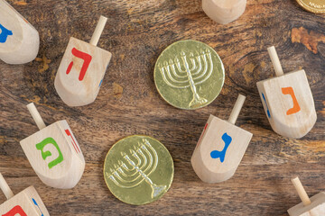 Hanukkah gelt and wooden dreidels on rustic background with copy space. Hebrew letters on dreidels...