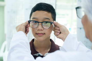 Smart young boy trying out new eyeglasses.