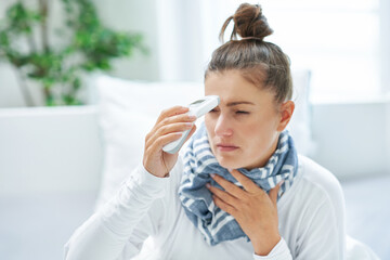 Young brunet woman sick in the bed with thermometer