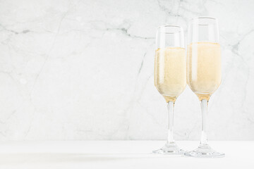 Festive background with sparkling champagne in  two glasses in white soft light interior on wood...