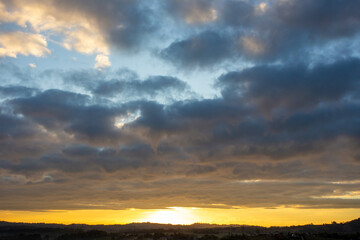 Morning view at morning sunrise, clouds in orange crimson colors. Silhouettes of houses roofs, trees, and a monastery on the hill. Colorful scenery skyline background.