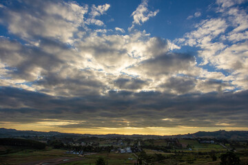 Obraz premium Morning view at morning sunrise, clouds in orange crimson colors. Silhouettes of houses roofs, trees, and a monastery on the hill. Colorful scenery skyline background.