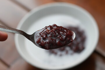 a bowl of black sticky rice porridge with coconut milk