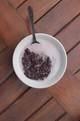 a bowl of black sticky rice porridge with coconut milk