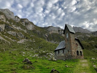 Beautiful shot of an aged church in the middle of a field surrounded by mountains