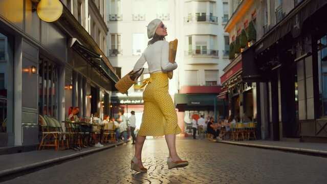 Happy girl in a yellow skirt with baguettes walking on the street