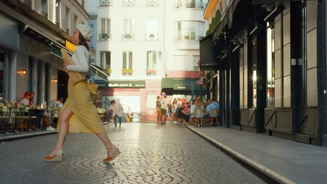 A young girl in a yellow skirt with baguettes walking from a French bakery in Paris