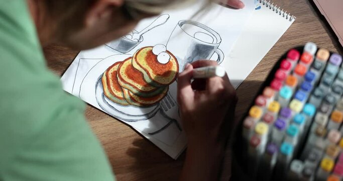 Person draws picture with eating pancakes and cup at home
