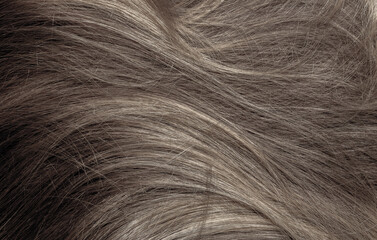 Brown hair close-up as a background. Women's long brown hair. Beautifully styled wavy shiny curls....