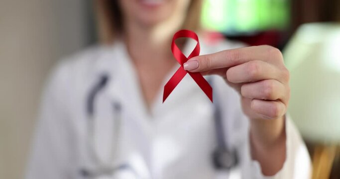 Doctor holds in hand red ribbon symbol of international day for protection of people from AIDS and hiv