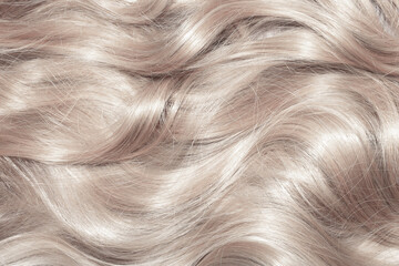 Blond hair close-up as a background. Women's long light brown hair. Beautifully styled wavy shiny...