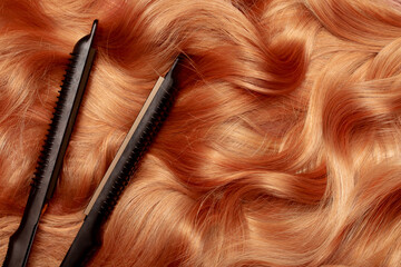 Naklejka premium Iron for straightening and styling hair in a beauty salon. Curling your hair into beautiful wavy curls with a hair straightener. Flat lay top view as background with place for text.