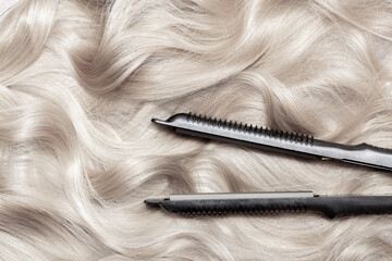 Naklejka premium Iron for straightening and styling hair in a beauty salon. Curling your hair into beautiful wavy curls with a hair straightener. Flat lay top view as background with place for text.
