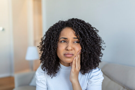 Portrait of unhappy African-American woman suffering from toothache at home. Healthcare, dental health and problem concept. Stock photo