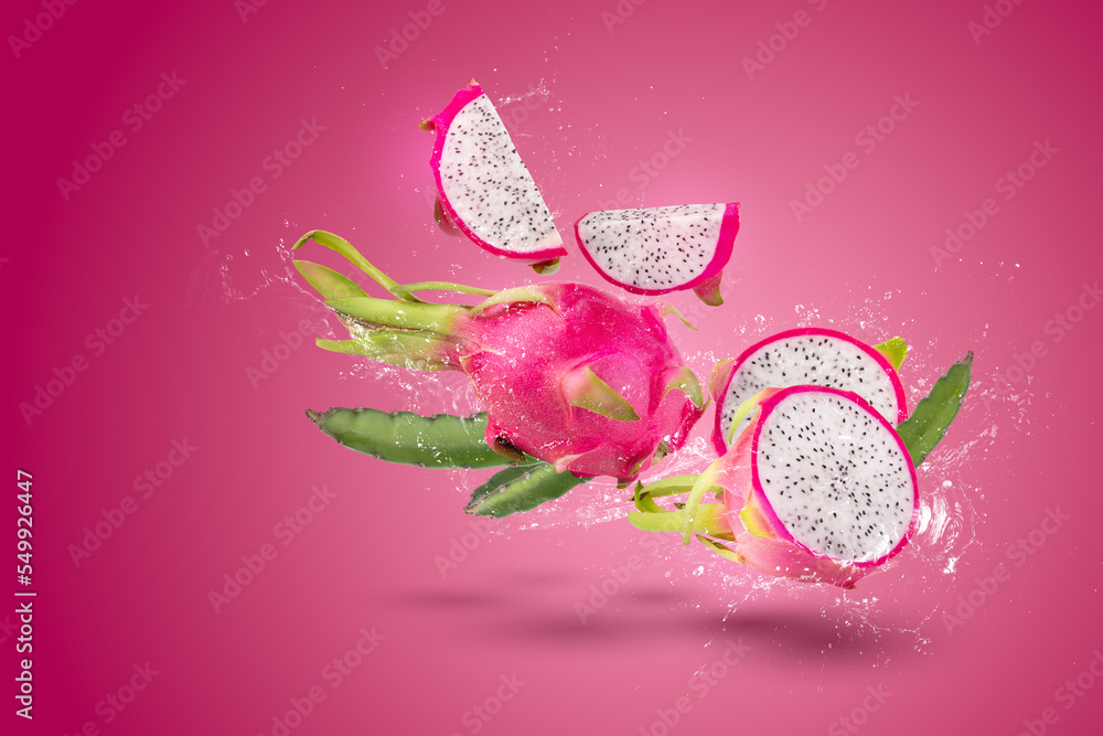 Sticker water splashing on ripe pitahaya fruit or dragon fruit with half isolated on red background - Stickers