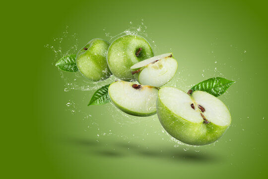 Water Splashing on Green apple and cut slice with seed on green background.