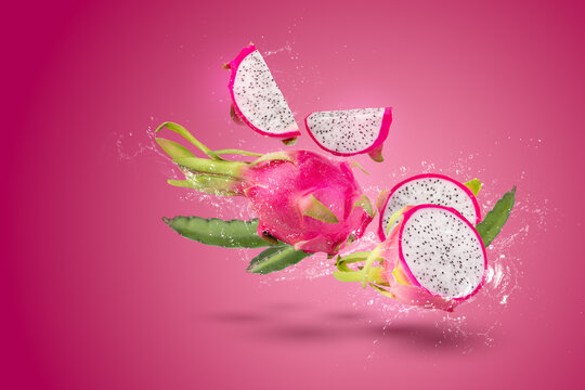 Water splashing on Ripe pitahaya fruit or dragon fruit with half isolated on red background