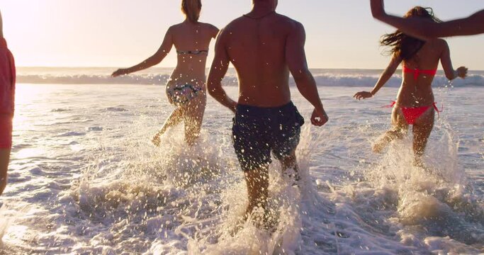 Running, freedom and summer with friends at beach for social, travel and water splash. Happy, vacation and destination with people in ocean of shoreline for holiday, happiness and swimming at sunset