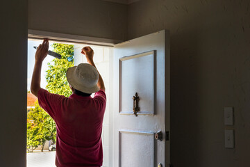 Man applying draught stopping foam tape to the door frame. Home maintenance to meet the healthy home standard. Auckland. - obrazy, fototapety, plakaty