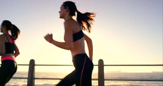 Fitness, exercise and women running by ocean for wellness, health and cardio in morning at sunrise. Nature, sports and girl friends do workout, run and marathon training on promenade together by sea