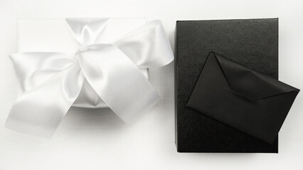 Gift white and black box with bow and envelope. White background. Holiday concept. Christmas. New Year. Valentine's Day.