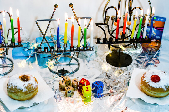 Jewish religious holiday hanukkah with glittering traditional chandelier menorah, spinning top toys (dreidel), a doughnut (sufganiyot).