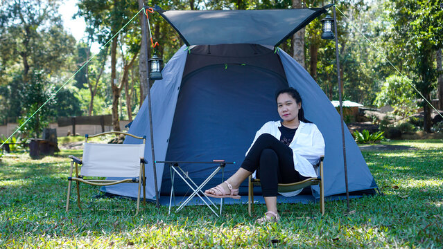 camping on vacation Asian woman in Thailand relaxing in an armchair near a tent in the countryside