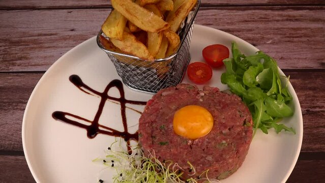 Steak Tartare with vegetables salad and french fries on dish. High quality 4k footage