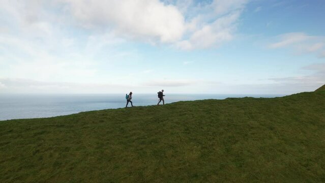 Man and a woman walking the ridgeline on Kalsoy Island in the Faroe Islands