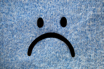 Sad face drawn on a blue sweater as blue background. Blue Monday concept in January. Isolated...