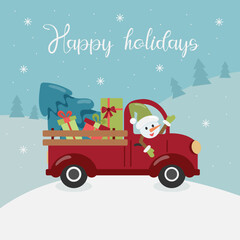 A red truck is carrying a Christmas tree and gifts, a snowman is driving. In the background are mountains and trees. Snowing