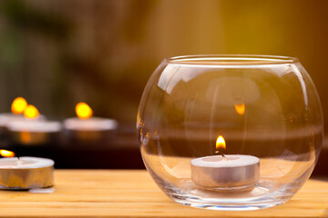Obraz na płótnie Canvas An image showing decorative miniature candles, one inside a glass bowl and others outside on a timber table top, ideas as a relaxation theme or mood background.