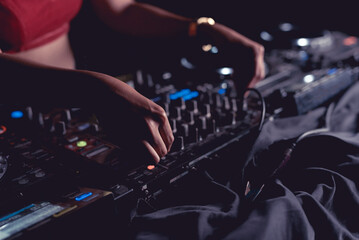An anonymous female DJ adjusting the EQ controls on the mixer.