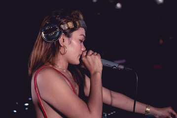 A female DJ singing or rapping on the microphones. Providing extra vocals to enhance the music. A...