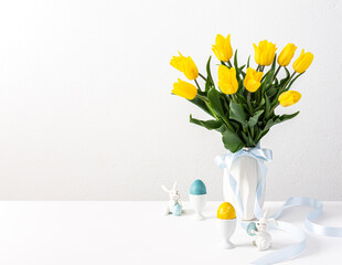 Fototapeta na wymiar Easter interior, yellow tulips in a vase and Easter eggs, cute bunnies
