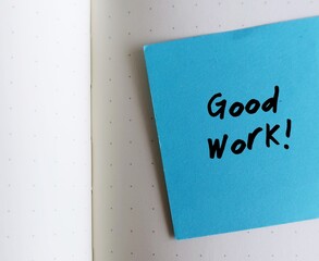 Office blue note on notebook with handwriting Good Work , compliment team or workers for the good work, giving praise to someone for a job well done