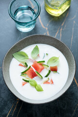 Cold soup with buttermilk, watermelon and cucumber on a dark-olive marble background, vertical shot, elevated view