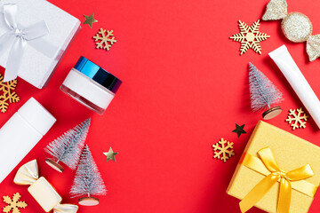 Fototapeta premium Cosmetic products, gift box and Christmas decoration and baubles on bright red background.