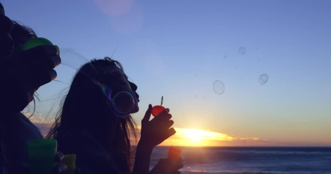 Sunset, beach bubbles and silhouette of friends on outdoor bonding time, have fun and relax on ocean sea shore. Blue sky, blowing and nature freedom for women on girl trip for peace, calm and beauty