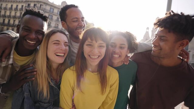 Travel with happy friends. Young smiling people looking at camera hugging. Group of multicultural boys and girls having fun outdoors celebrating vacations Erasmus together in Europe. Modern lifestyle.