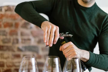 Fotobehang barman uncorks a bottle to fill glasses for wine tasting © Carlo